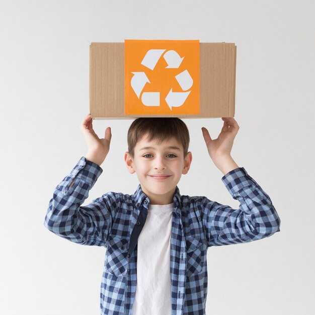 Porträt des niedlichen Jungen, der mit Recyclingbox aufwirft