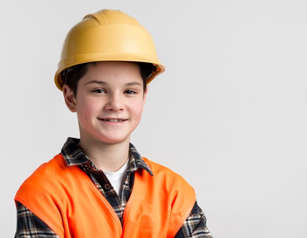 Porträt des niedlichen Jungen, der mit Schutzhelm aufwirft