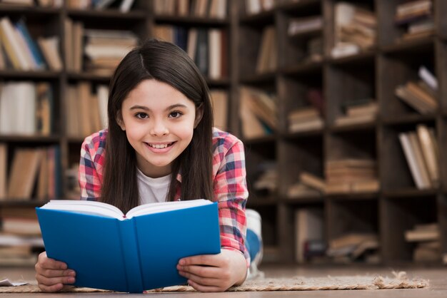 Porträt des niedlichen jungen Mädchens, das ein Buch hält