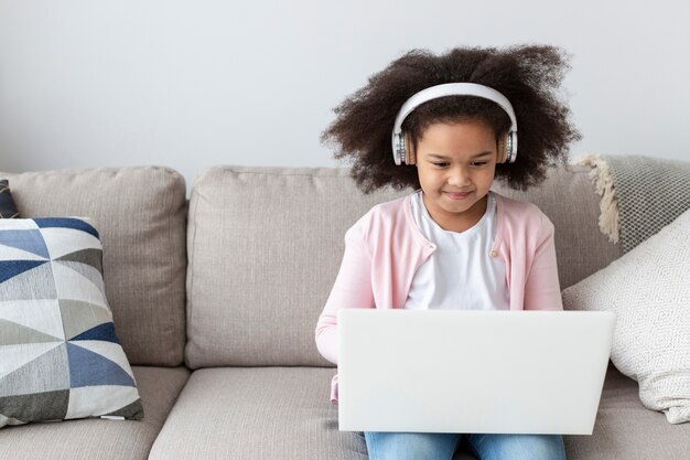 Porträt des niedlichen jungen Mädchens unter Verwendung eines Laptops