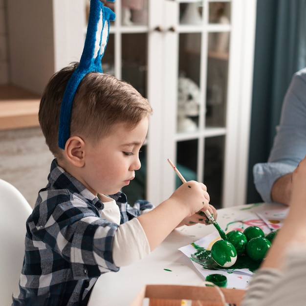 Kostenloses Foto porträt des niedlichen kleinen jungen, der eier für ostern malt