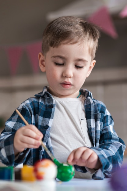 Porträt des niedlichen kleinen Jungen, der Eier für Ostern schmerzt