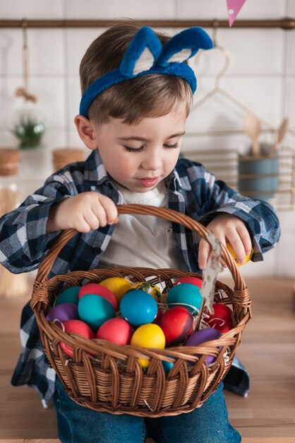 Porträt des niedlichen kleinen Jungen, der einen Eierkorb hält