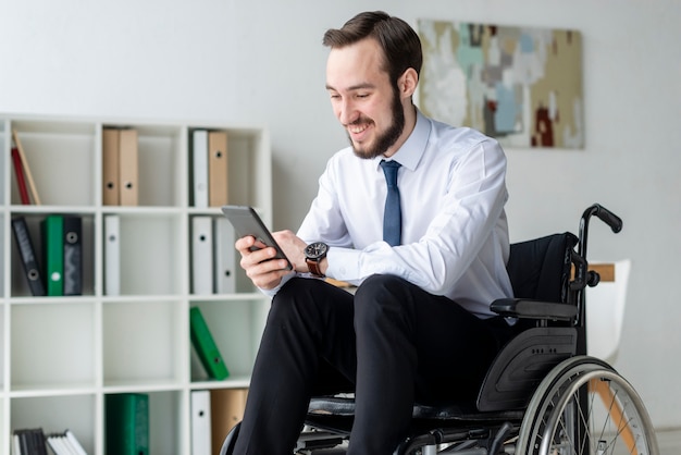 Porträt des positiven erwachsenen Mannes unter Verwendung des Mobiltelefons