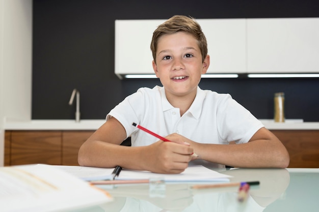 Porträt des positiven Jungen, der Hausaufgaben macht