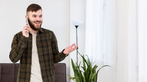 Porträt des positiven Mannes, der am Telefon spricht