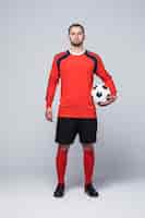 Kostenloses Foto porträt des professionellen fußballspielers im roten hemd lokalisiert auf weiß