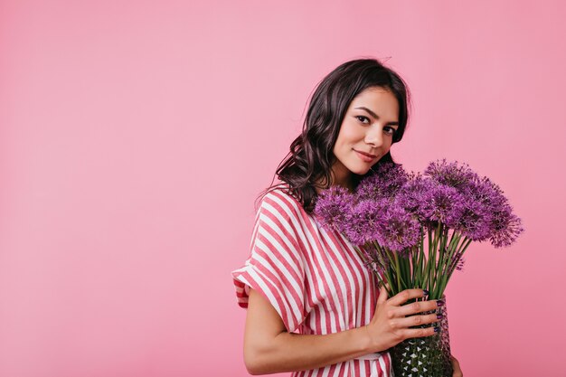 Porträt des romantischen Mädchens mit lila Blumen. Brünette im rosa Kleid sieht süß aus.