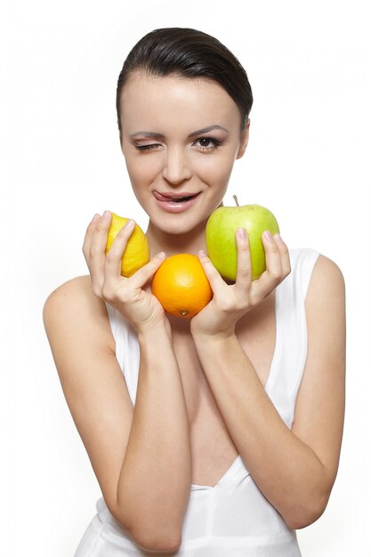 Porträt des schönen glücklichen lächelnden Mädchens mit Früchten Zitrone und grünem Apfel und Orange lokalisiert auf Weiß