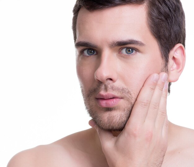 Porträt des schönen jungen Mannes mit Hand nahe dem Gesicht auf weißer Wand.