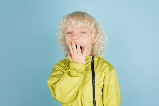 Porträt des schönen kaukasischen kleinen Jungen isoliert auf blauer Wand