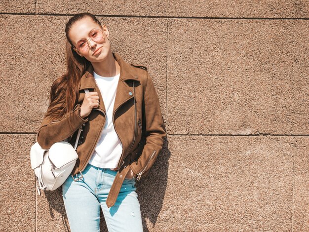 Porträt des schönen lächelnden Brunettemodells kleidete in der Sommerhippie-Jacke und in der Jeanskleidung an