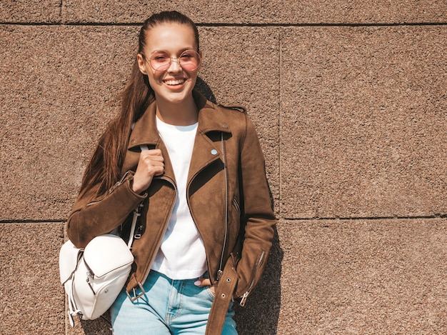 Porträt des schönen lächelnden Brunettemodells kleidete in der Sommerhippie-Jacke und in der Jeanskleidung an