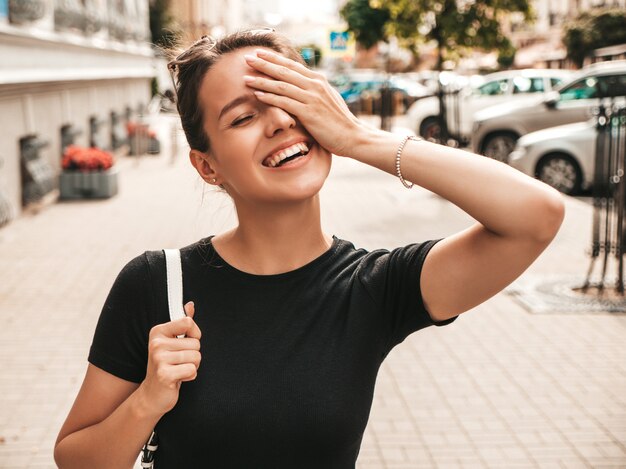 Porträt des schönen lächelnden Modells kleidete in der Sommerkleidung an. Modisches Mädchen, das in der Straße aufwirft. Lustige und positive Frau, die Spaß hat