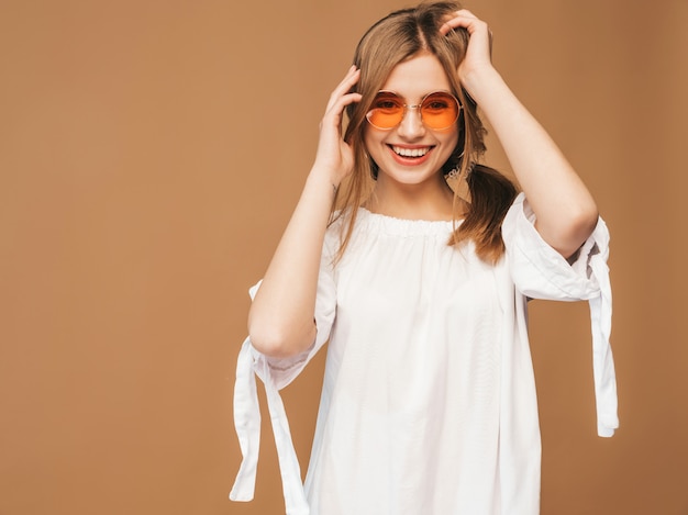 Porträt des schönen lächelnden netten modells mit den rosa lippen. mädchen im weißen sommerkleid. model posiert in sonnenbrille