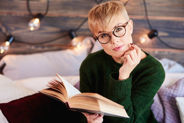 Kostenloses Foto porträt des schönen mädchens, das ein buch im bett liest