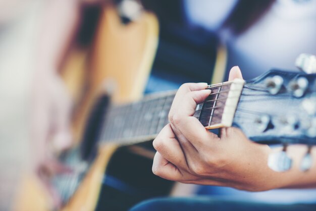 Porträt des schönen Mädchens die Gitarre mit Fahrrad an der Natur spielend