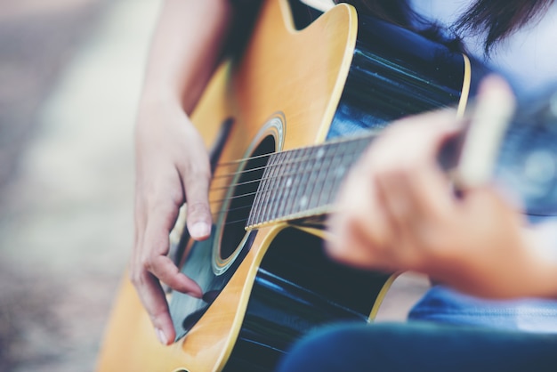 Porträt des schönen Mädchens die Gitarre mit Fahrrad an der Natur spielend