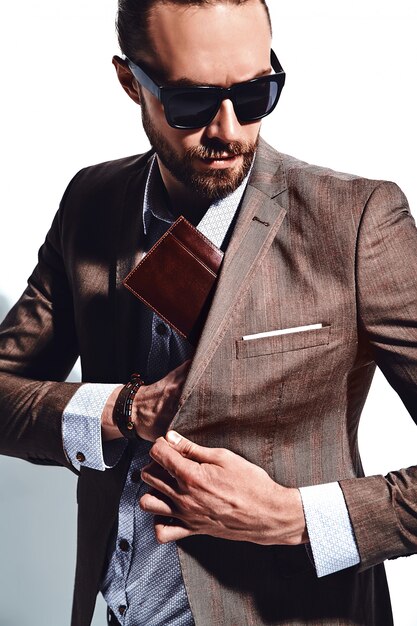 Porträt des schönen modischen Hipster-Geschäftsmannmodells der Mode, gekleidet in eleganten braunen Anzug in Sonnenbrille