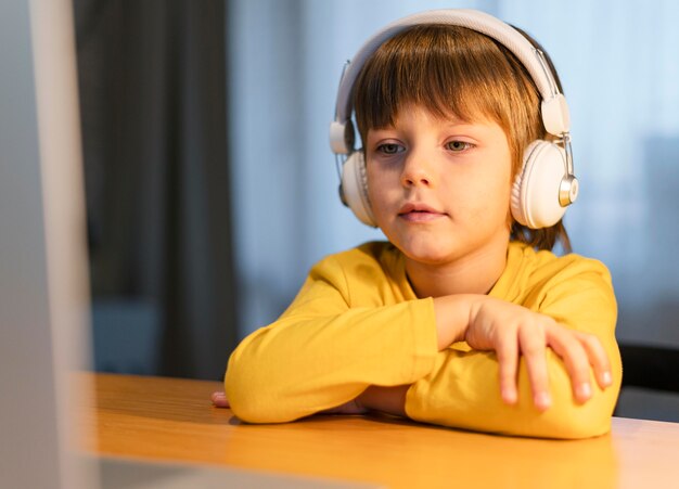 Porträt des Schuljungen im gelben Hemd, das virtuelle Klassen nimmt