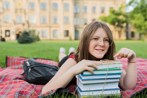 Porträt des Schulmädchens legend auf Decke mit Büchern