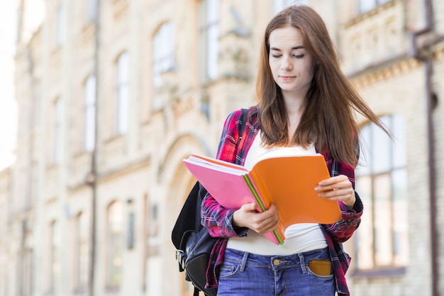 Porträt des Schulmädchens mit Buch in der Stadt