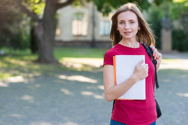 Porträt des Schulmädchens mit Büchern im Park