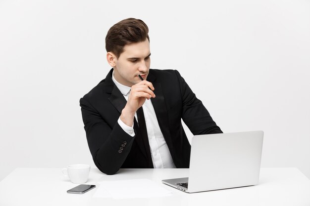 Porträt des selbstbewussten Managers, der am Schreibtisch sitzt. Porträt des Geschäftsmannes, der am Computer arbeitet. Erfolgreicher formaler Mann in seinem neuen modernen Büro.