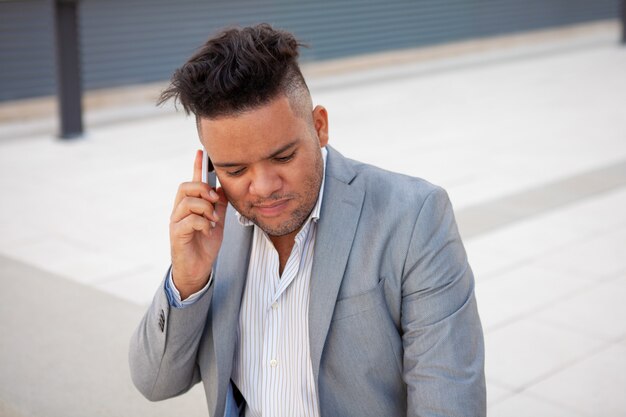 Porträt des starken Geschäftsmannes, der mit Kunden am Telefon spricht