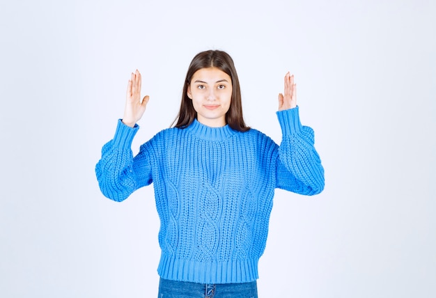 Porträt des Teenagermädchens in der blauen Strickjacke, die etwas steht und zeigt.