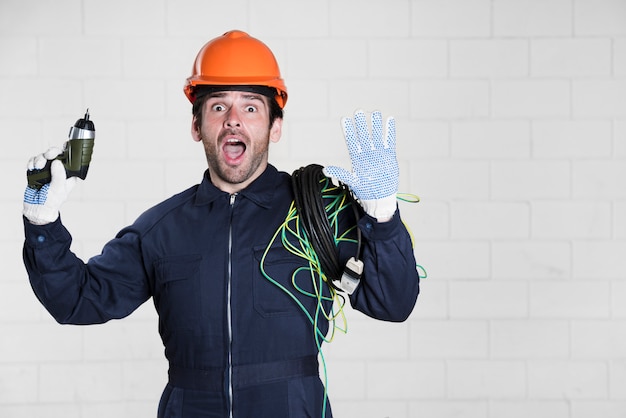 Porträt des überraschten männlichen Elektrikers, der Kamera mit dem Mund offen betrachtet