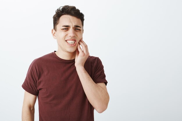 Porträt des unzufriedenen leidenden jungen männlichen Modells im roten T-Shirt