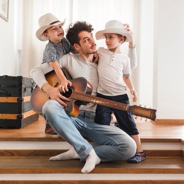 Porträt des Vaters mit seinen zwei Söhnen, die Gitarre halten