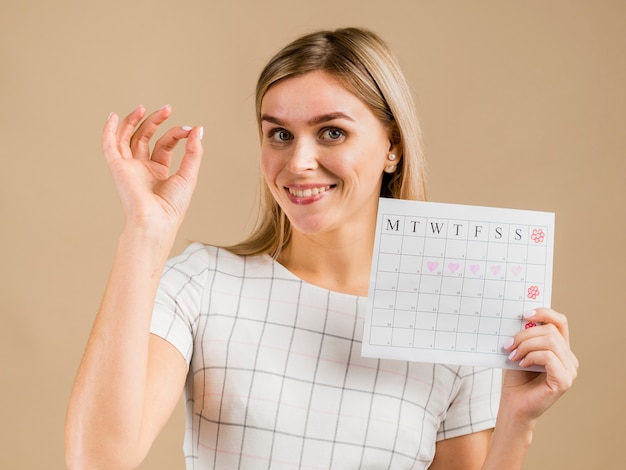 Porträt des weiblichen haltenen Menstruationskalenders des smiley