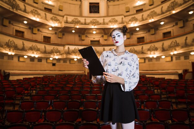 Porträt des weiblichen Pantomimen stehend in einem Auditorium, das Skript hält