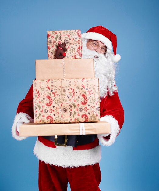 Porträt des Weihnachtsmannes, der Stapel von Weihnachtsgeschenken hält