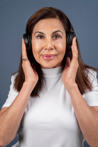 Porträt einer älteren Frau, die Musik über Kopfhörer hört