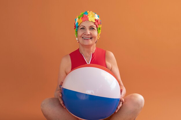 Porträt einer älteren Frau mit geblümter Badekappe und Ball
