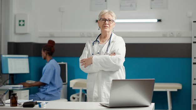 Kostenloses Foto porträt einer ärztin mit medizinischem fachwissen, die sich zuversichtlich über das gesundheitssystem im kabinett fühlt. arzt wartet darauf, kontrollbesuche und beratungstermine mit dem patienten zu beginnen.