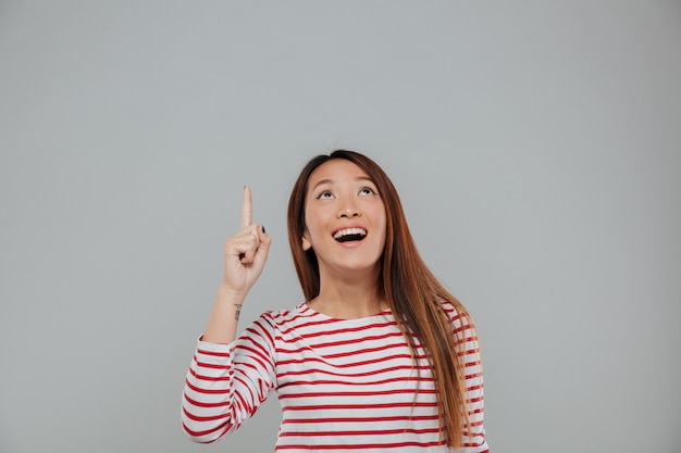 Porträt einer amüsierten glücklichen asiatischen Frau, die Finger zeigt