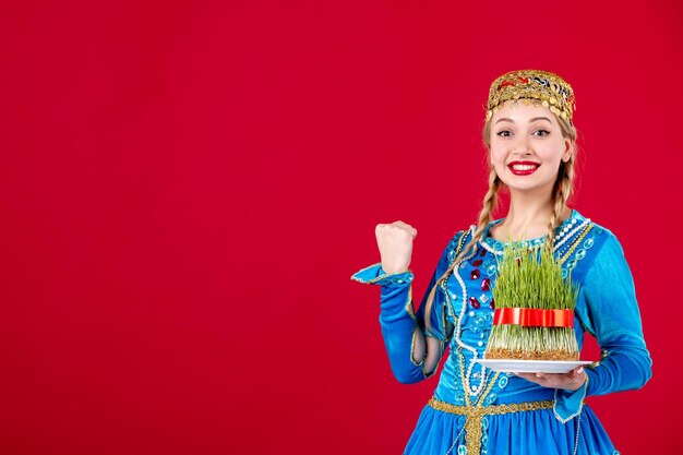 Porträt einer aserbaidschanischen Frau in traditioneller Kleidung mit grünem Semeni Studio auf rotem Hintergrund ethnischen Frühling erschossen