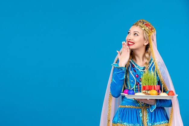 Porträt einer aserbaidschanischen Frau in traditioneller Kleidung mit Novruz Xonca blauem Hintergrund Frühling ethnischen Geld Tänzer Foto