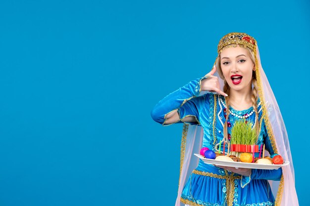 Porträt einer aserbaidschanischen Frau in traditioneller Kleidung mit Novruz Xonca posiert auf blauem Hintergrund Frühling ethnisches Geld