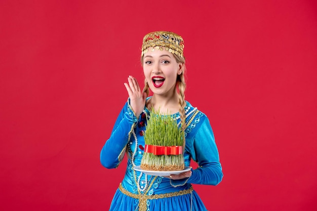 Kostenloses Foto porträt einer aserbaidschanischen frau in traditioneller kleidung mit semeni studio schoss roten hintergrund novruz konzept frühling