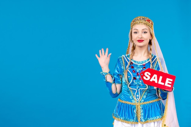 Porträt einer aserbaidschanischen Frau in traditioneller Kleidung mit Verkauf Namensschild blauem Hintergrund Frühling Shopping Tänzerin