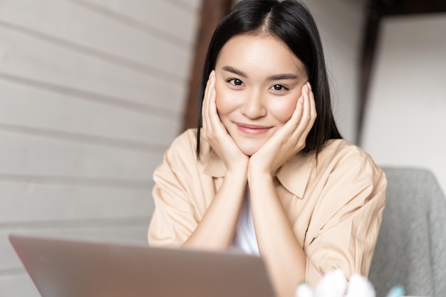 Porträt einer asiatischen frau, die von zu hause aus am laptop arbeitet und sich mit dem computer entspannt in...