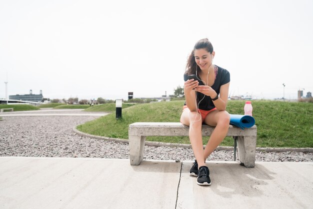 Porträt einer athletischen Frau, die ihr Handy in einer Trainingspause benutzt. Sport und Gesundheit Lebensstil.