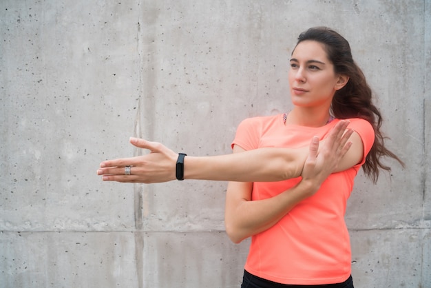 Porträt einer athletischen Frau, die ihre Arme vor dem Training im Freien streckt. Sport und gesunder Lebensstil.