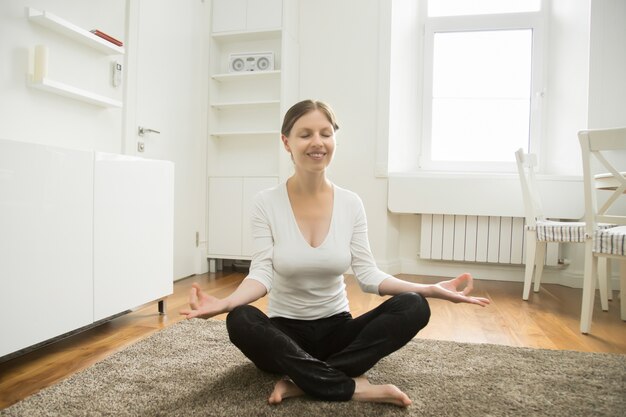 Porträt einer attraktiven Frau sitzt in Lotus-Pose