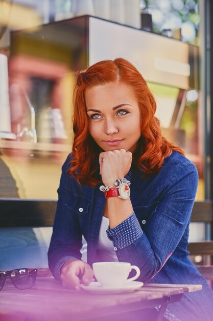 Porträt einer attraktiven rothaarigen Frau, die Kaffee in einem Café trinkt.